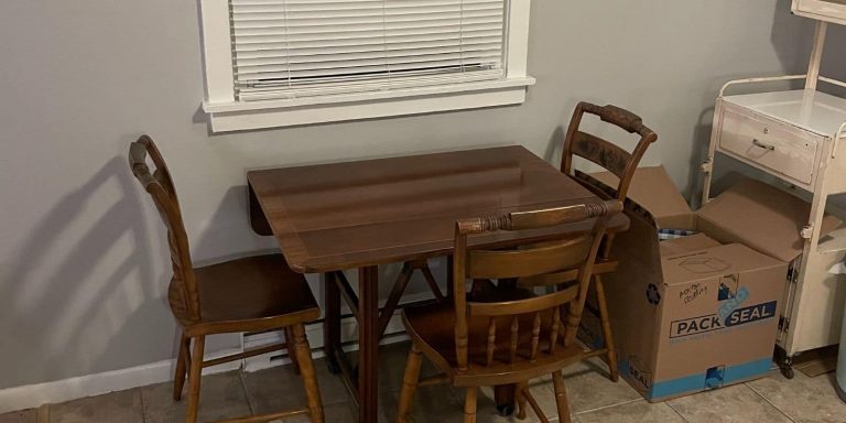 A table, chairs, and boxes in a small apartment