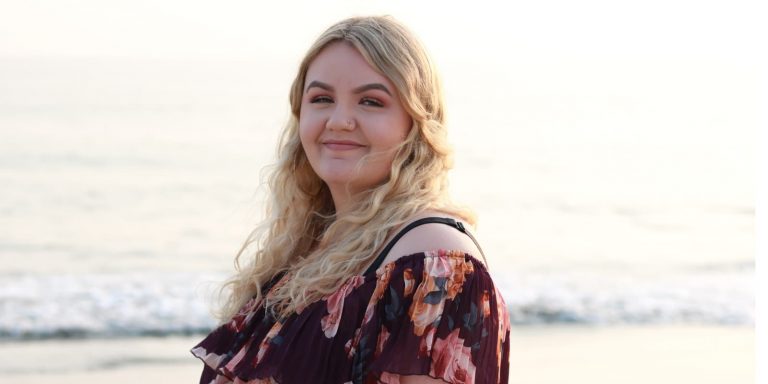A woman standing on the beach and smiling