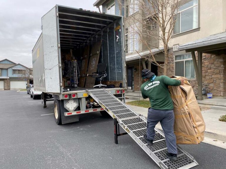 A worker carries a large box up a loading ramp and into a U-Pack trailer