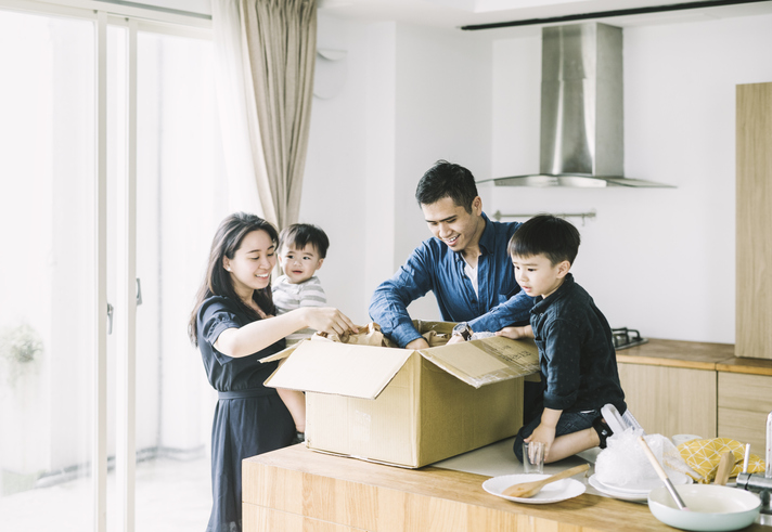 Family unpacking moving boxes in kitchen