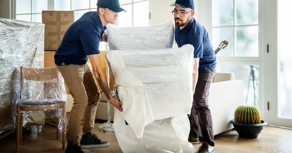 Two professional packers carrying an armchair