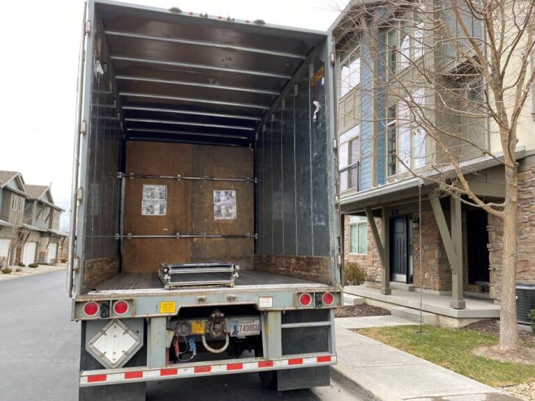 An open U-Pack trailer parked next to a home